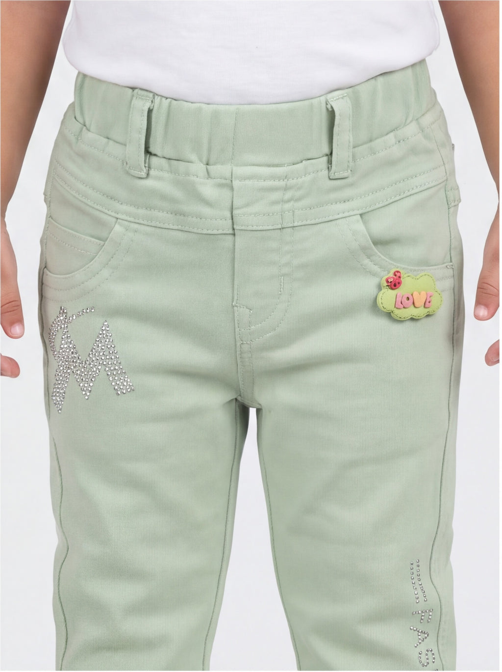Close-up of waist, pockets, rhinestone M and LOVE patch on mint green denim pants