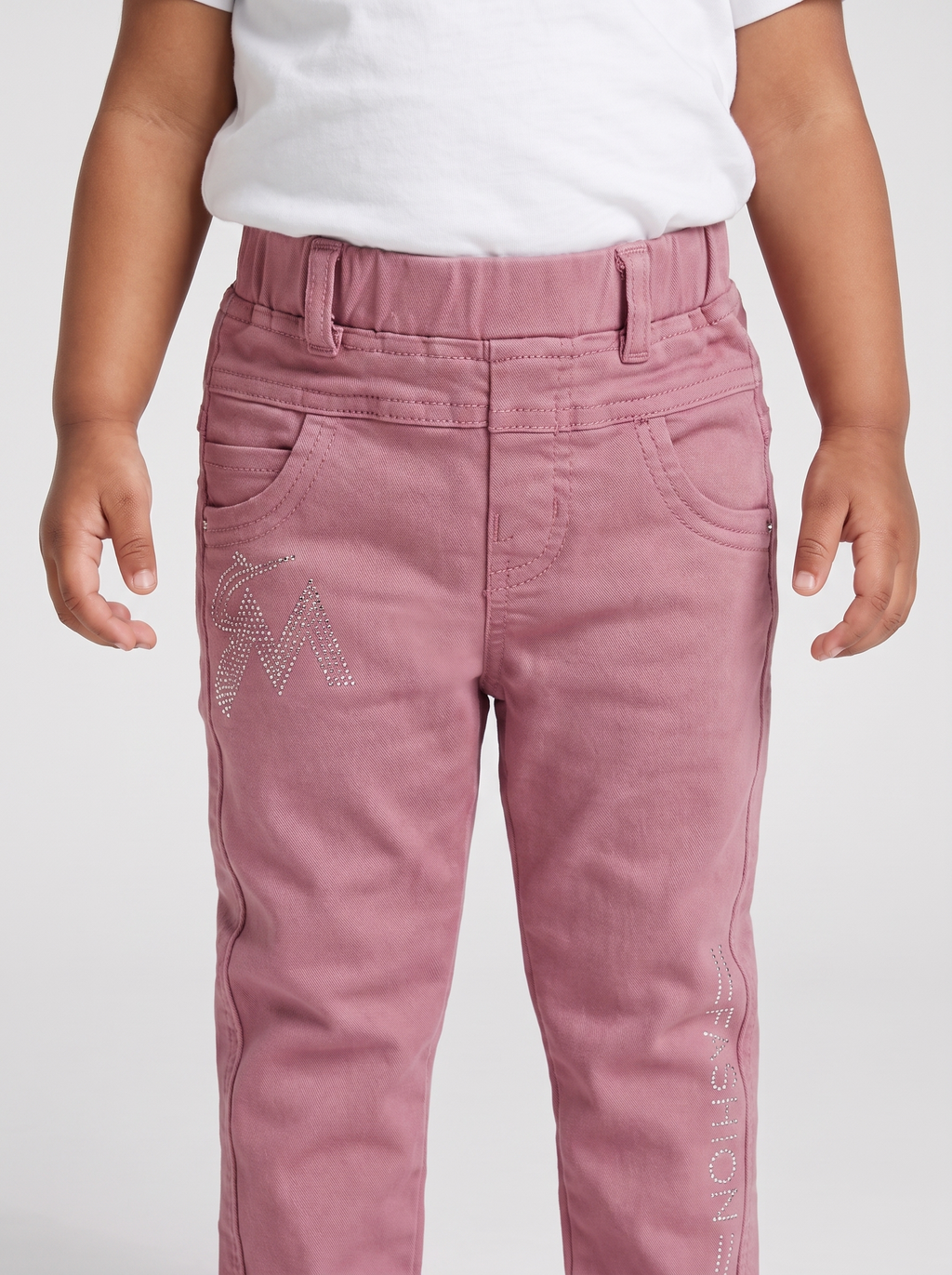 Close-up of elastic waist, pockets and rhinestone M design on pink denim pants