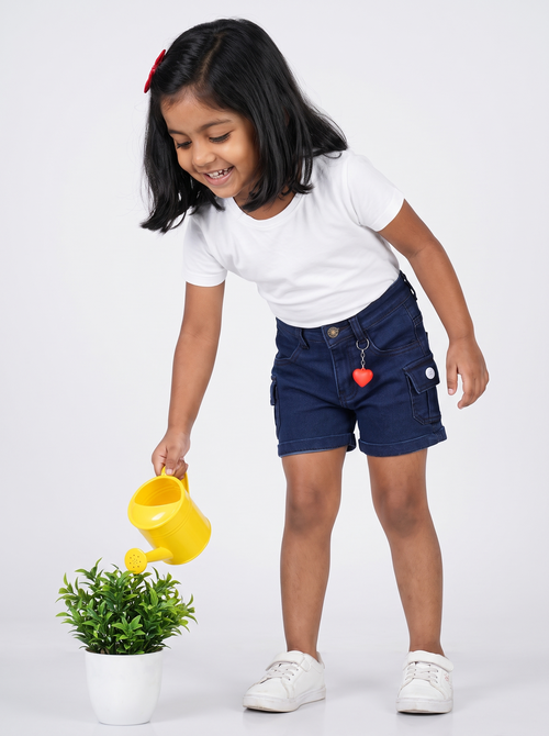 Girl wearing navy denim cargo shorts, watering a plant