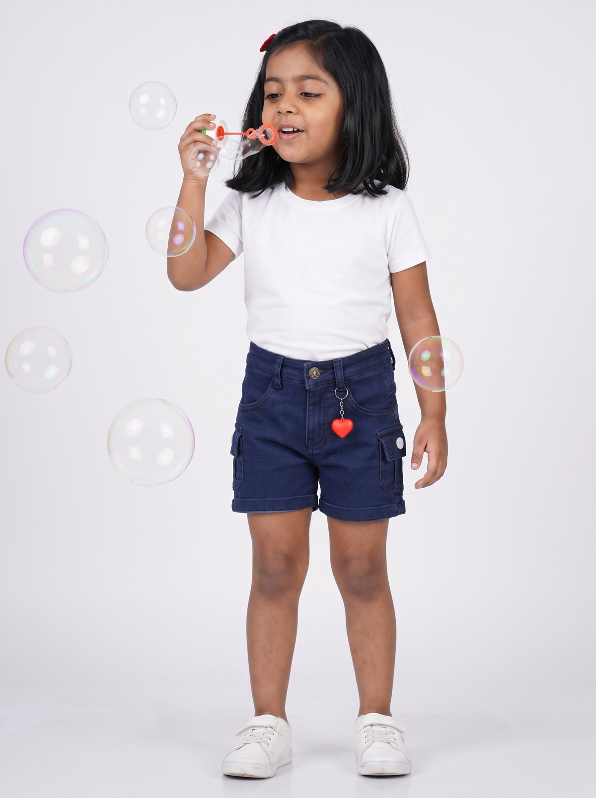 Girl wearing navy denim cargo shorts, blowing bubbles