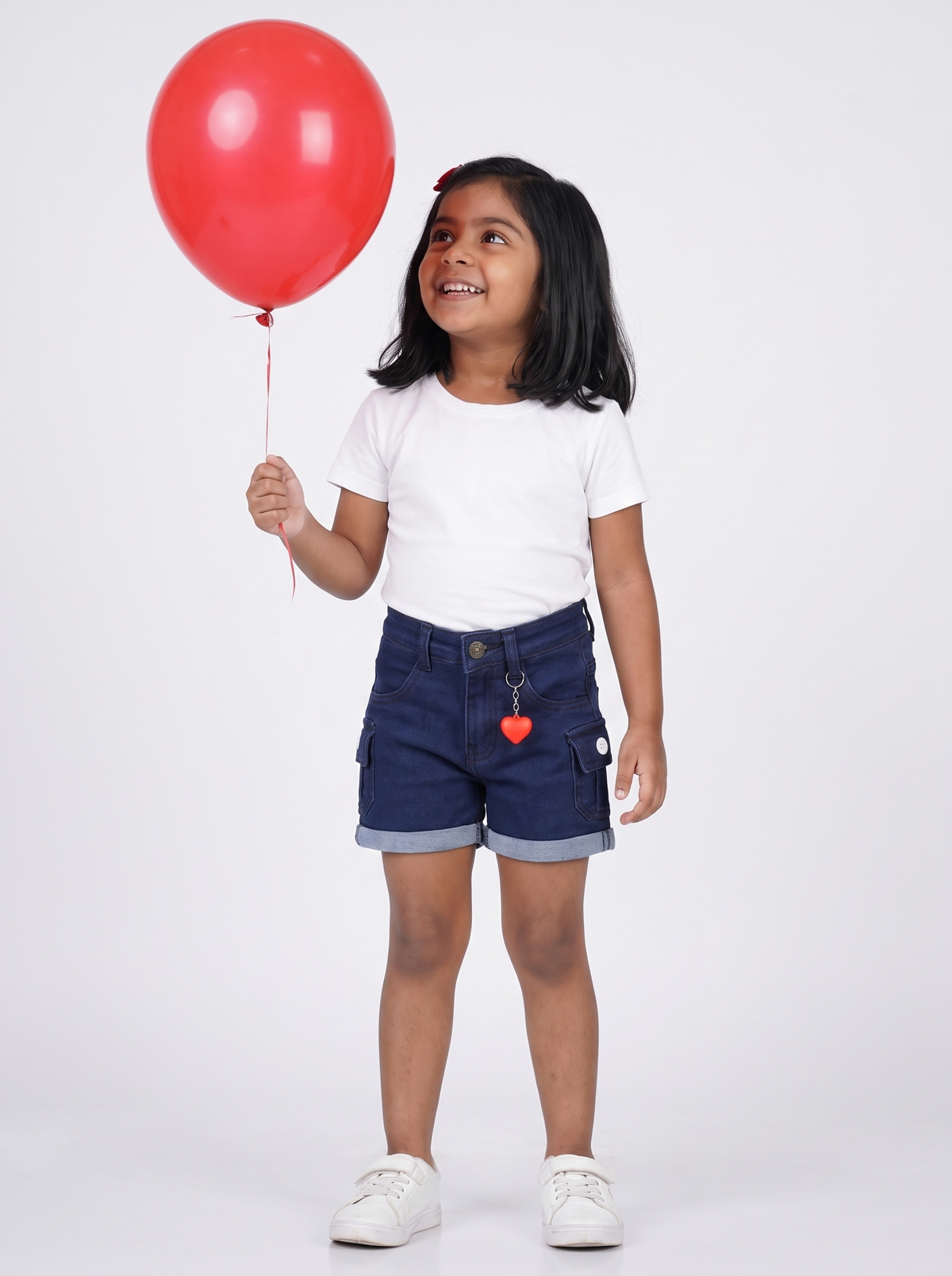 Girl wearing navy denim cargo shorts, holding a red balloon